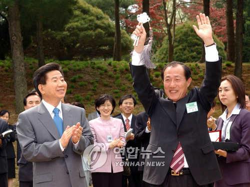 2003년 4월 18일, 당시 이원종 충북지사가 노무현 대통령으로부터 청남대 정문 모형열쇠를 전달받고 주민들에게 인사하고 있다. [연합뉴스 제공]