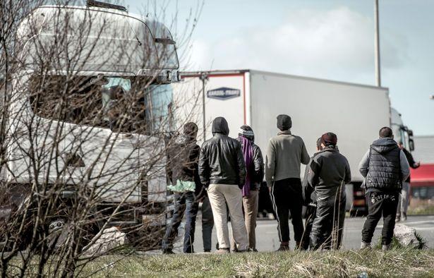 프랑스 칼레 항구를 지나는 트럭 사이로 보이는 이민자들. [사진=연합뉴스제공]