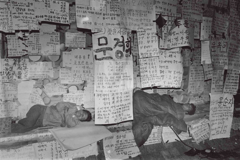 '이산가족을 찾습니다' 방송이 진행 중이던 KBS 앞마당에서 신상이 적힌 글판을 내걸고 대기중인 이산가족들[위키백과]